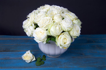lush bouquet of white roses stands on blue wooden table