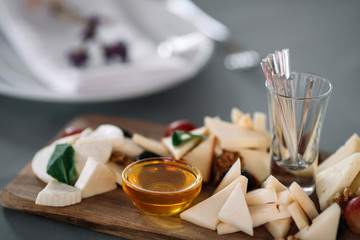 Different sorts of cheese with honey on a cutting board