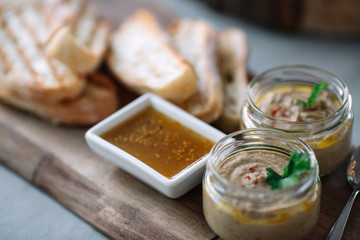 Two cans of pâté mustard and bread on the cutting board