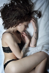 Fototapeta na wymiar Beautiful woman with tattoo in lace underwear on the bed.