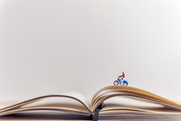 Miniature traveler riding a motorbike over opened book. Travel concept