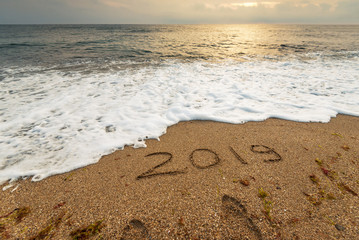 2019 handwritten in sand of tropical beach.
