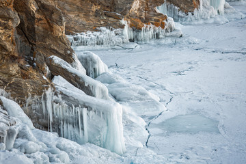Icy rocky shore on lake Baikal. Large hanging icicles.