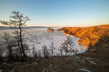 Fototapeta na wymiar Olkhon island in early spring. Shaman rock and Baikal lake at sunset.