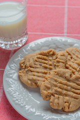 Plate of peanut butter cookies with milk and flowers in the background