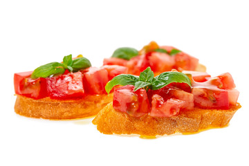 Italian traditional bruschetta with toasted baguette, chopped tomato, green leaf of basil and olive oil isolated on white background, close up