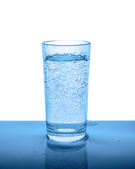 mineral water in transparent glass with drops and bubbles isolated over white, blue background, close up