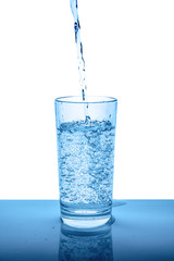 pouring mineral water in transparent glass with drops and bubbles isolated over white, blue background, close up