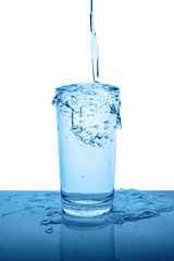 overflowing mineral water in transparent glass with drops and bubbles isolated over white, blue background, close up