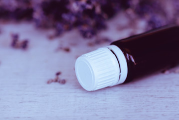 Herbal essential oil and lavender flowers on wooden background. Close up and copy space.