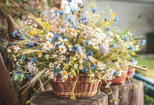 Wild flowers in a basket on a rustic background. Vintage scenery.