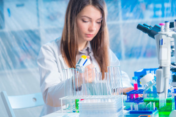 student woman with multi pipette and other PCR items in microbiological / genetic laboratory