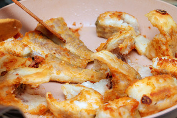 Pieces of fish fried in a hot pan
