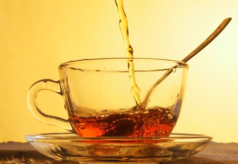 Tea is poured into a wide glass Cup. A Cup stands in a glass saucer.