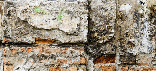Grunge old bricklaying wall fragment from red bricks and damaged plaster background.