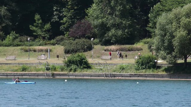 un canoista passa sul fiume mentre sul percorso si cammina e si corre a piedi
