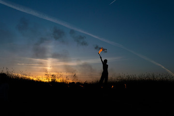 A man with a torch at sunset. Fire show and a lot of the bright sparks in the night