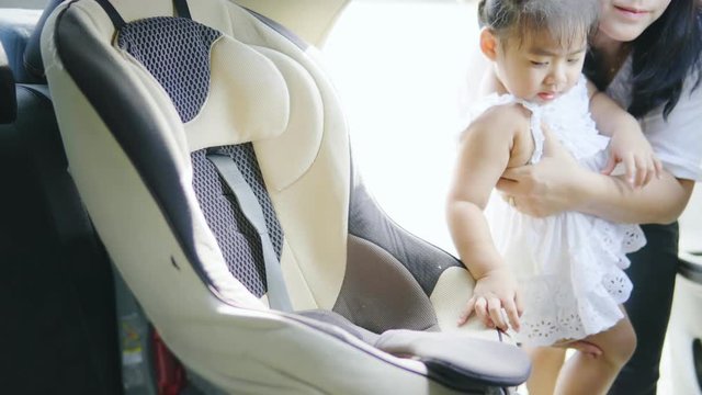 Beautiful Asian Mother Putting Baby In Car Seat