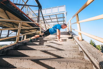 Outdoor workout. Man makes push up on the stairs