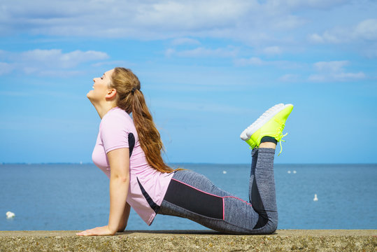 Woman doing yoga next to sea