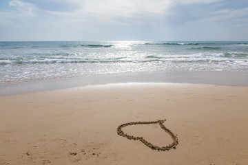 Cuore disegnato sulla sabbia bagnata in riva al mare