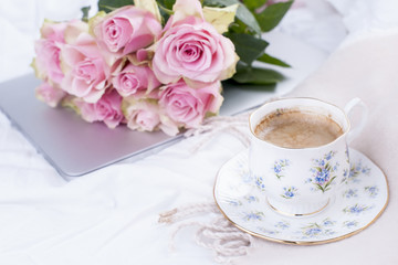 A bouquet of pink roses in the bed, a computer and a morning aromatic coffee. Copy spase.