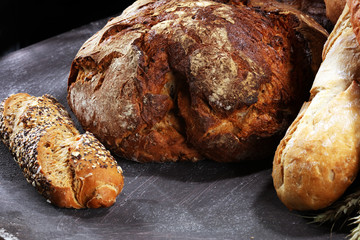 Different kinds of bread and bread rolls on board from above. Kitchen or bakery