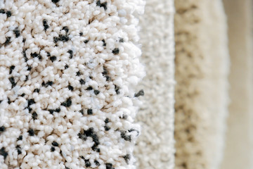 Carpets of shades of gray and white are hanging for sale with copy space. close-up