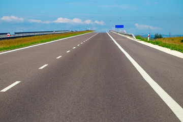 empty asphalt road and field and blue sky with clouds