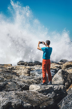 man taking pictures at stormy sea with mobile