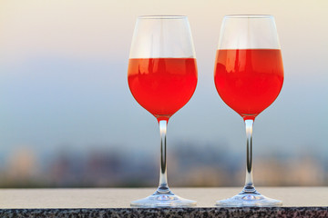 glasses filled with a cocktail are romantically standing against the background of panoramas of the city