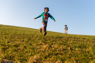 Boy running down grass hill