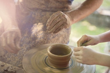 Child in Clay Pottery Making Class. Potter sculpting clay pot on a turning pottery wheel
