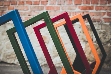 colorful blue green red orange and black metal cycle parking places in poor urban backstreet environment with old dirty brick wall background
