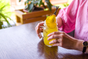 close up of happy woman drinking yellow cocktail with orange slice at cafe - drinks, people and...