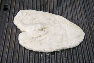 Fladenbrotteig auf der gusseisernen Grillplatte bereit gegrillt zu werden