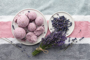 Handmade lavender bath bombs and lavender flowers on striped bath towel, top view