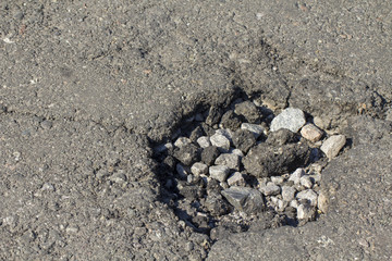 Pothole in asphalt near the sewer hatch, in the middle of the street