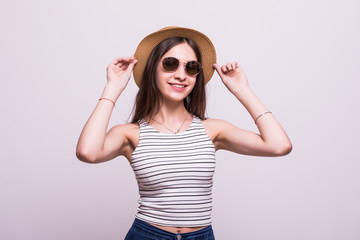 Portrait of a smiling attractive woman in summer dress and hat posing while standing and looking at camera isolated over white background