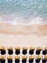 Aerial view of amazing turquoise sea with brown straw umbrellas and sun loungers. Beautiful sunny summer day in Sardinia, Mediterranean sea, Italy..
