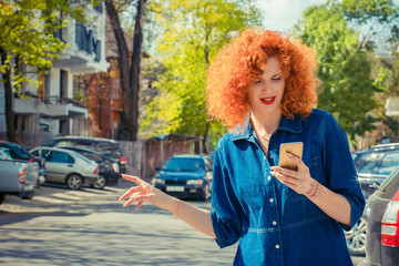 woman holding mobile phone; hitch hiking in the city street