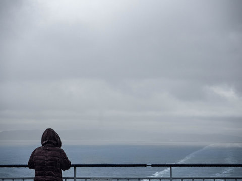 Mujer bajo la lluvia a bordo de un barco, mirando al horizonte en Oslo, verano de 2017.