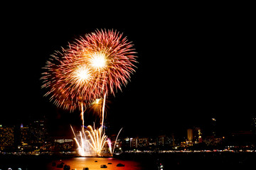 Many flashing fireworks with night cityscape background celebrate New Year.