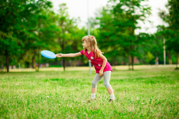 Little girl play with flying disk in motion, playing leisure activity games in summer park