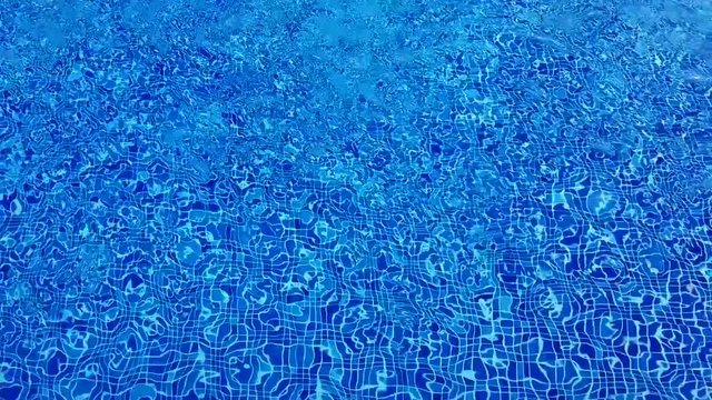 Swimming pool water with ripples and refractions on blue tiles