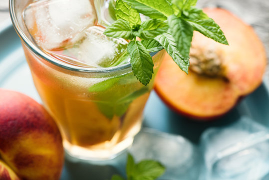Refreshing iced tea with ripe peaches on rustic background, selective focus, toned image