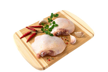 Raw chicken thighs with thyme  on cutting board, on a white background.