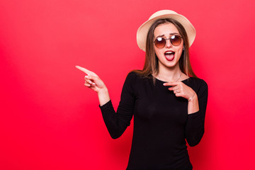 Naklejka premium Woman showing pointing on red background. Very fresh and energetic beautiful young girl smiling happy presenting on red background.