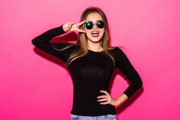Portrait of a pretty woman showing peace gesture with two hands isolated over pink background