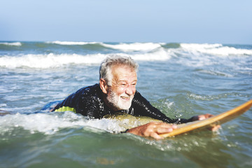 A senior man on a surfboard - obrazy, fototapety, plakaty